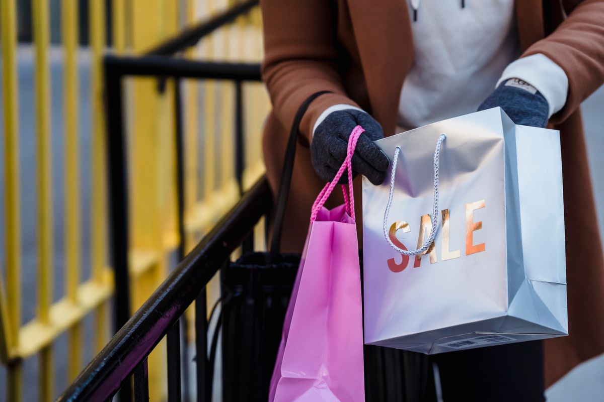 A shopper holding paper shopping bags outdoors